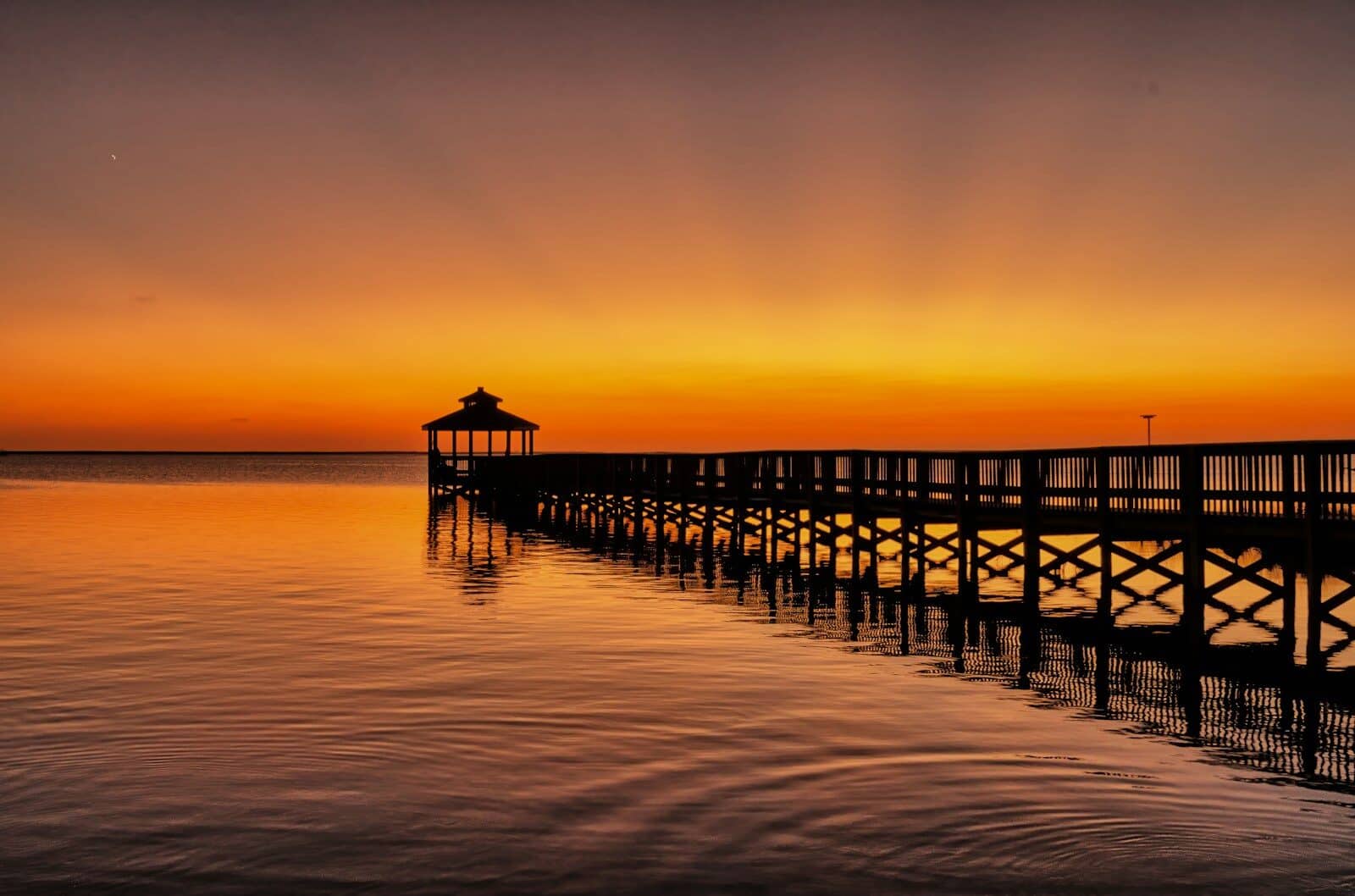 A long Outer Banks pier stretching into the Atlantic Ocean at sunset
