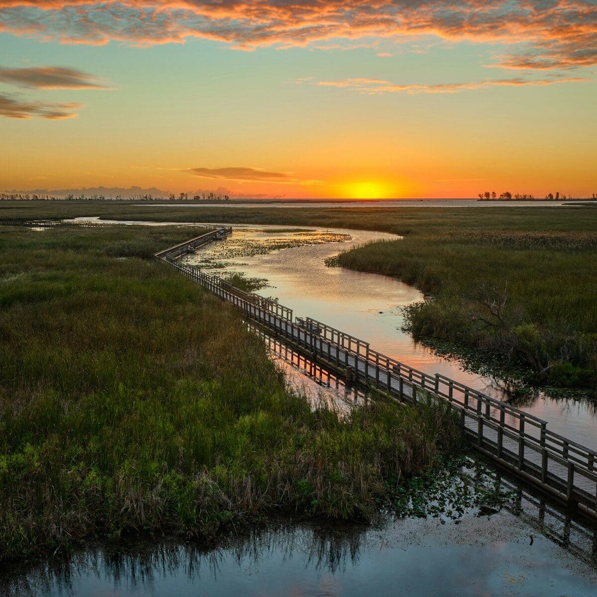 Wooden boardwalk crossing an OBX salt marsh at sunset on the sound side of the Outer Banks