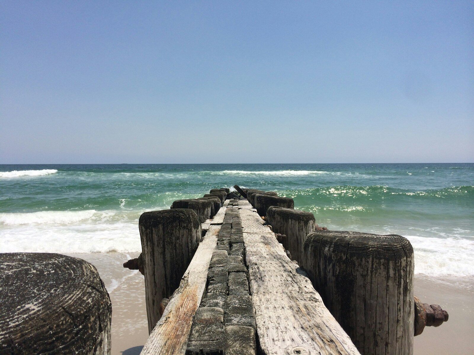 Wooden pier extending into the Atlantic on the Outer Banks showing tide line on pilings