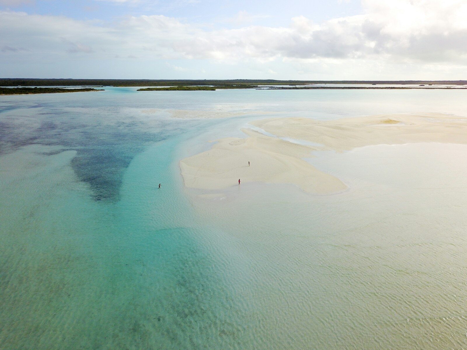 Shallow turquoise water over a sandbar revealed at low tide along the Outer Banks coast