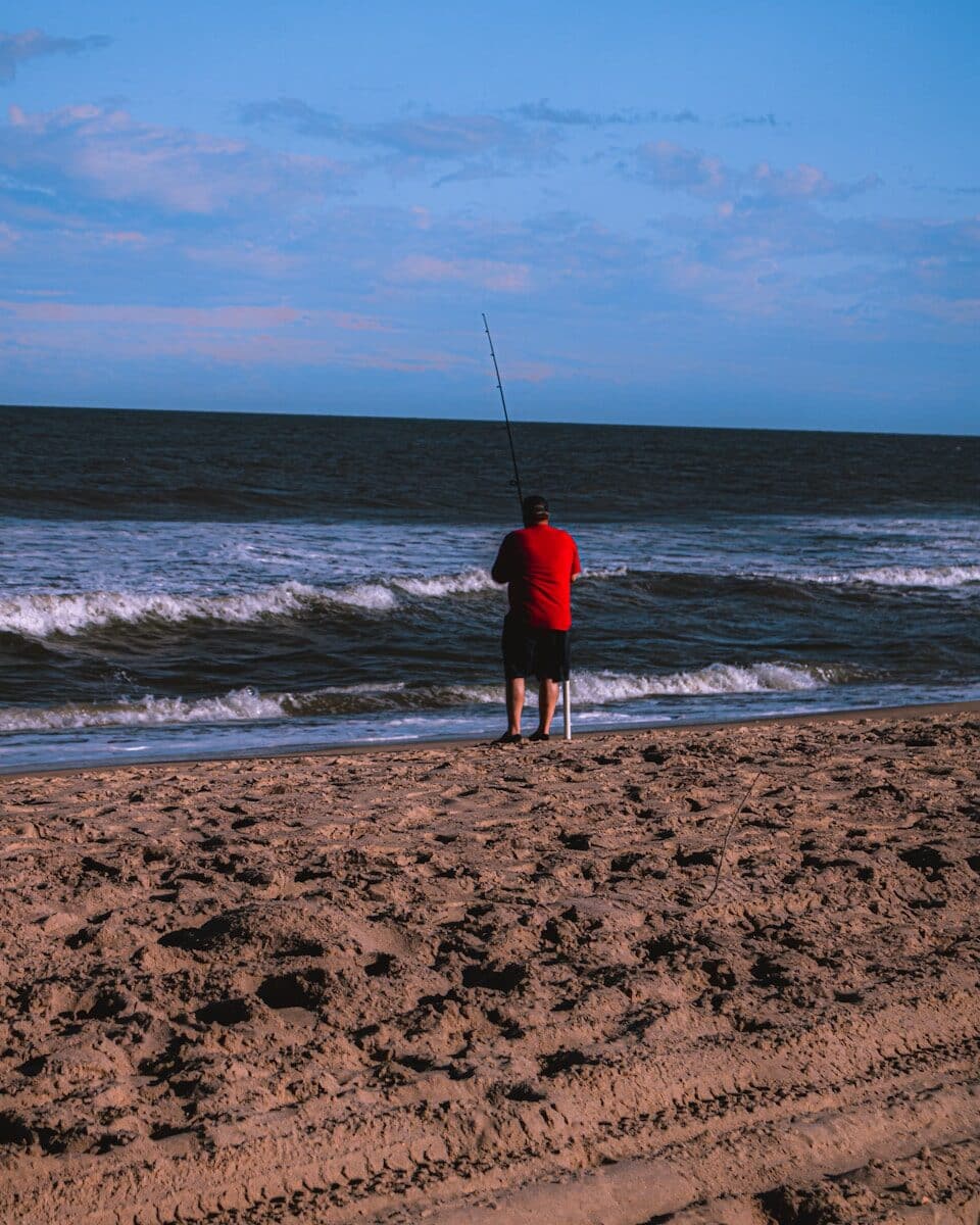 Angler surf fishing on an Outer Banks beach at low tide along the OBX shoreline
