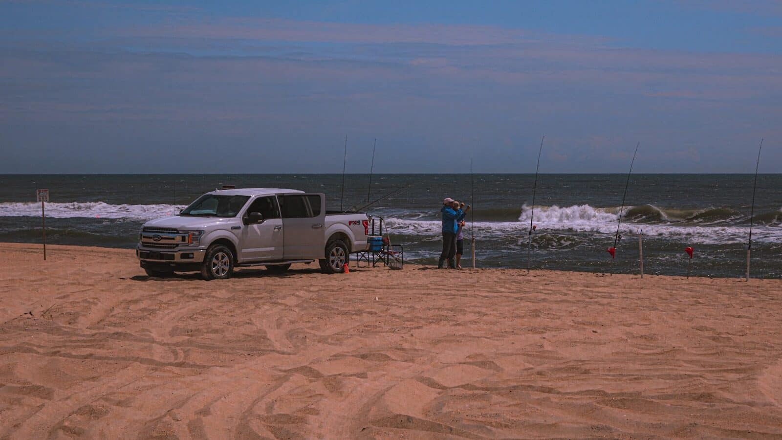 Pickup truck driving on the sand at low tide for surf fishing on the Outer Banks beach