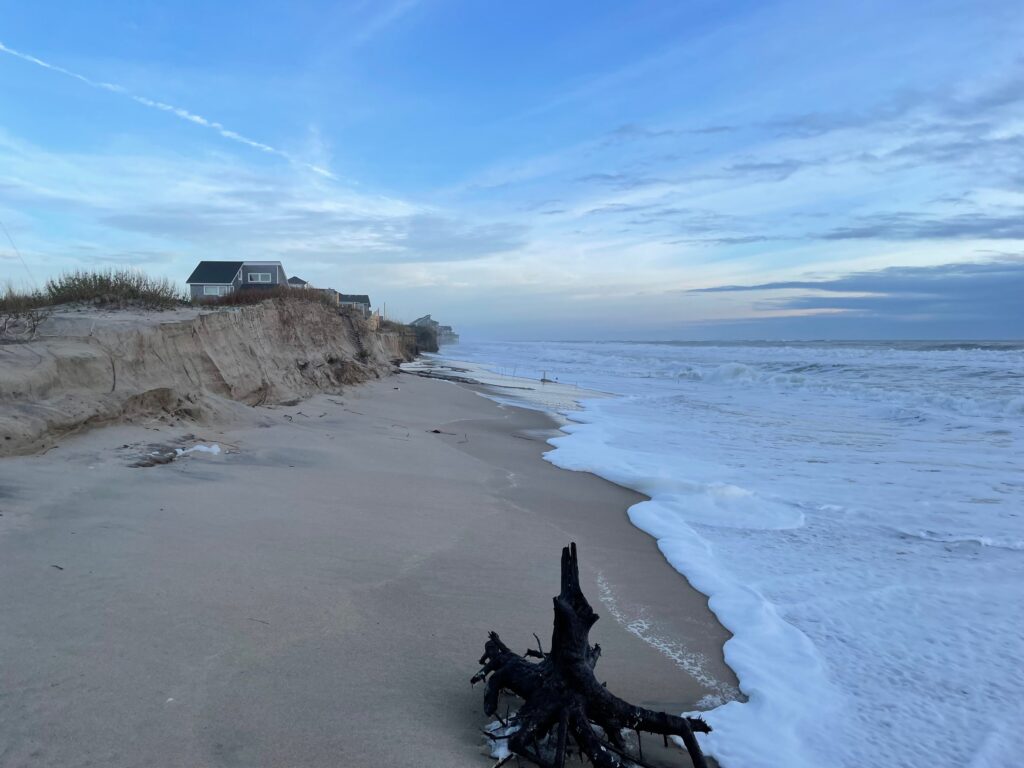 An eroded sand scarp and narrow beach at Buxton with the surf running close in.