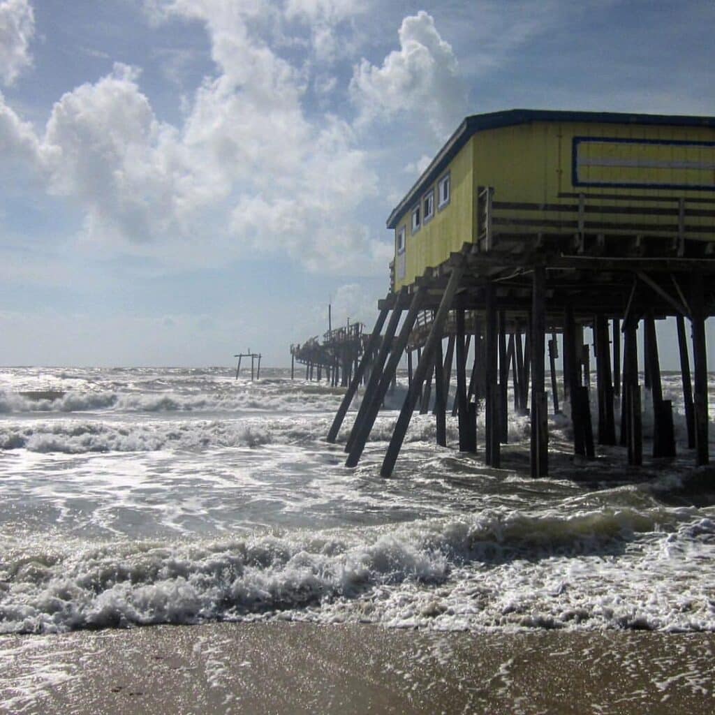 Surf breaking around the pilings of the old Frisco pier close to high tide.